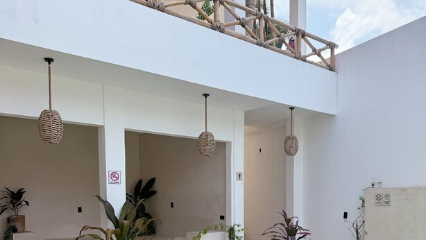A pool area with a person sitting on the edge, surrounded by potted plants and a wooden deck. - Casa Hamaca Nayarit (Chacala)