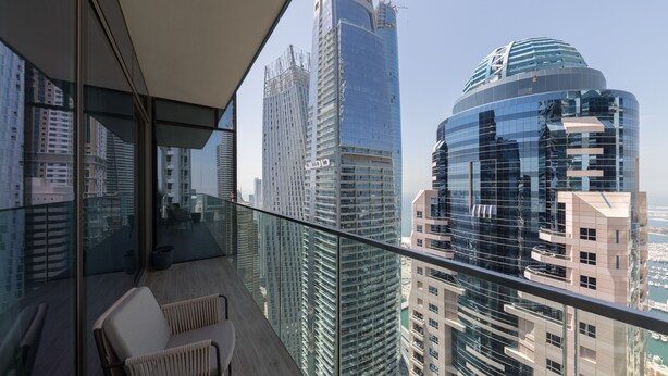 A balcony with a view of high-rise buildings, including a distinctive curved skyscraper.
