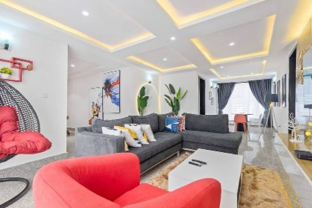 A modern living room with a grey sectional sofa, red armchair, and a coffee table.