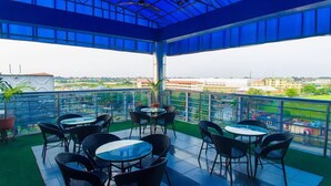 A covered outdoor seating area with tables and chairs, overlooking a cityscape. - MountRoyal Centre Hotel and Suites (Lagos)