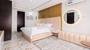 A modern bedroom with a bed, bedside table, and a round mirror. - MountRoyal Centre Hotel and Suites (Lagos)