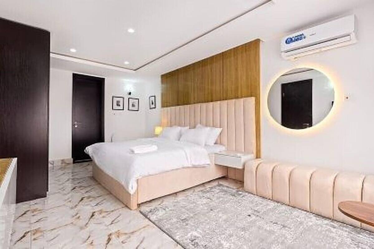 A modern bedroom with a bed, bedside table, and a round mirror.