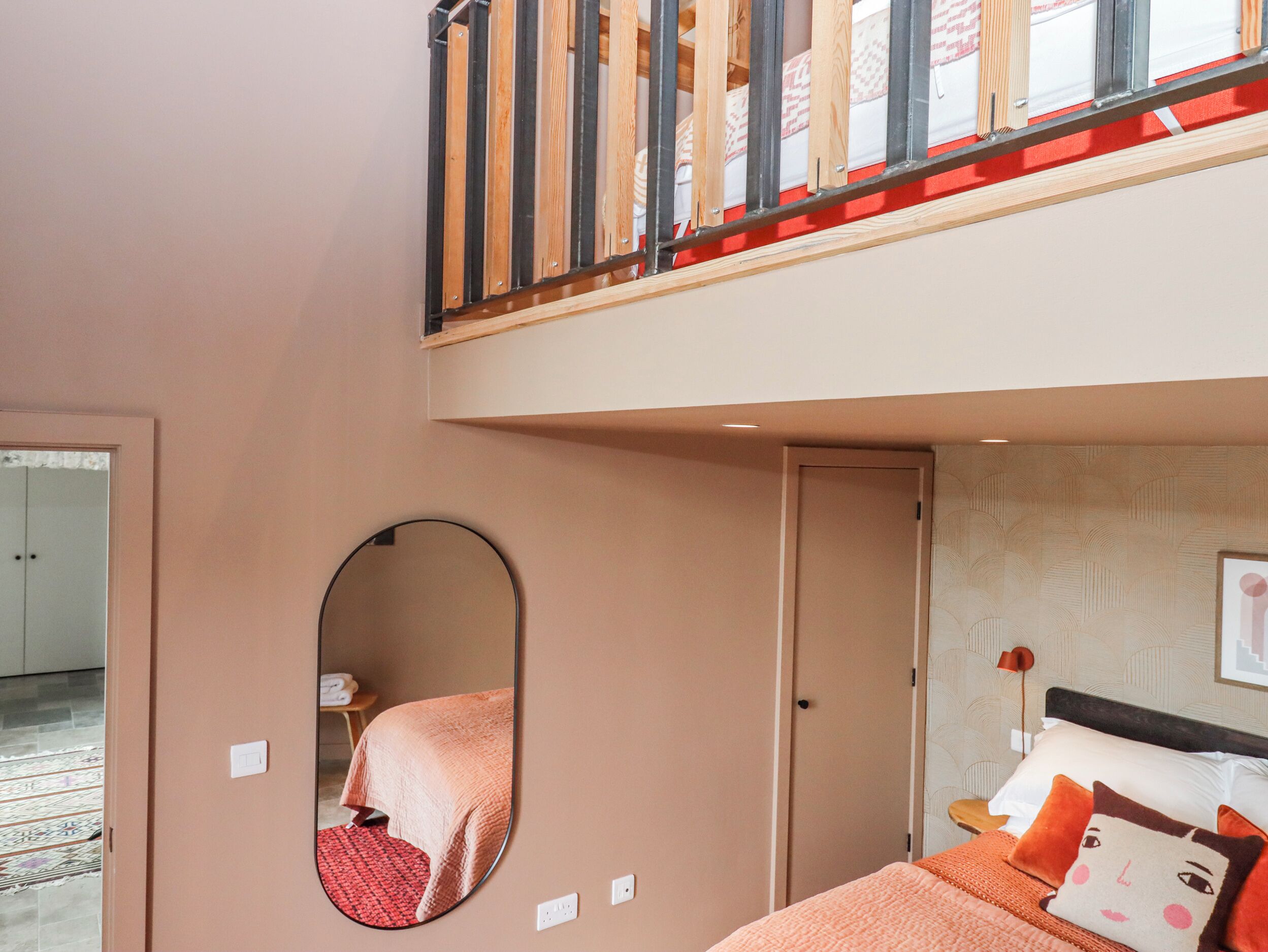 A bedroom with a bed, a mirror, a wardrobe, and a staircase.