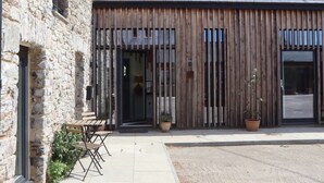 A rustic building with a stone facade, wooden slats, and a tiled roof. - 3 Caddaford Barns (Buckfastleigh)