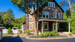 A two-story house with a porch, a stone border, and a white fence. - Chester County Oasis with Pool, Modern Ammenities, Tranquil and Private (West Chester)