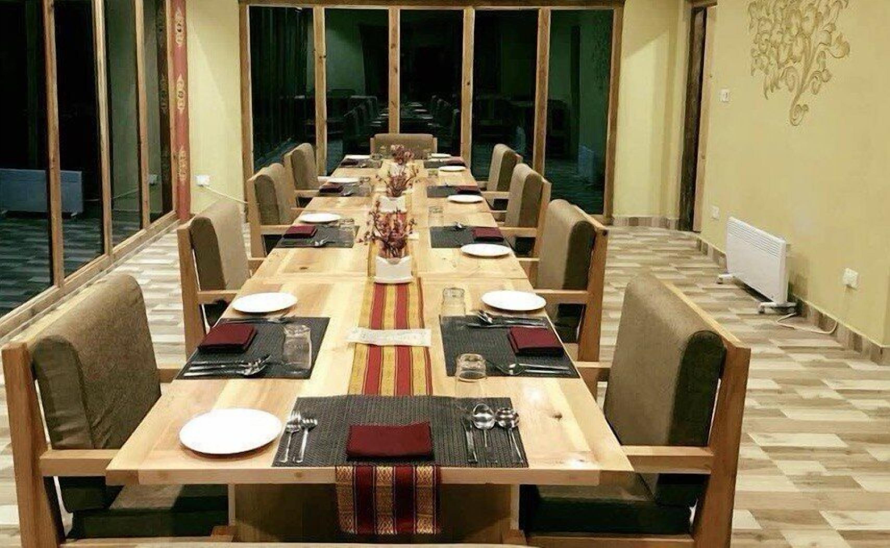 A long dining table set for a meal with chairs on both sides, a decorative centerpiece, and a radiator on the wall.
