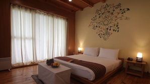 Ein Schlafzimmer mit einem großen Bett, einem Nachttisch, einem Fenster mit Vorhängen und einer floralen Wanddekoration.