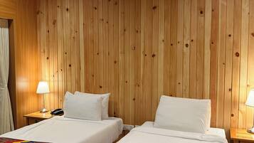 A room with two beds, wooden walls, and a ceiling fan.