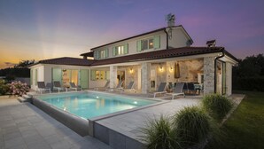 A two-story house with a swimming pool, outdoor seating, and a well-maintained garden.
