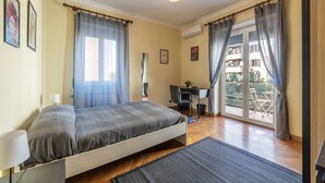 Un dormitorio con una cama, un escritorio y vistas al balcón exterior.