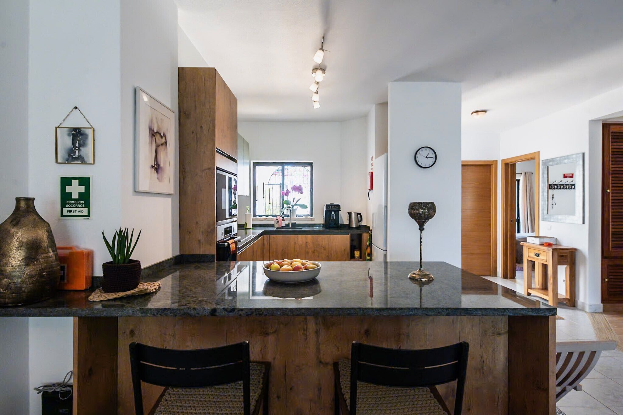 Een moderne keuken met een centraal eiland, houten kastjes en een groot raam.