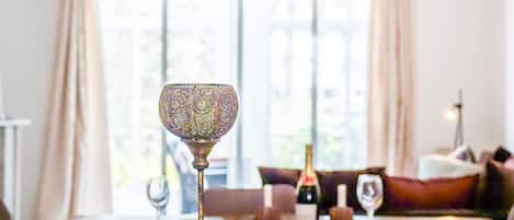 Een eettafel met een decoratief glas en een fles wijn.