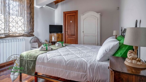 Un dormitorio con cama, armario de madera, televisión y ventana con cortinas.