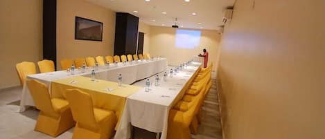 A conference room with a long table, yellow chairs, and a projector screen.