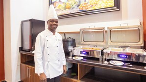 Disposición de bufé con un chef de pie, un refrigerador y dos dispensadores automáticos de bebidas.