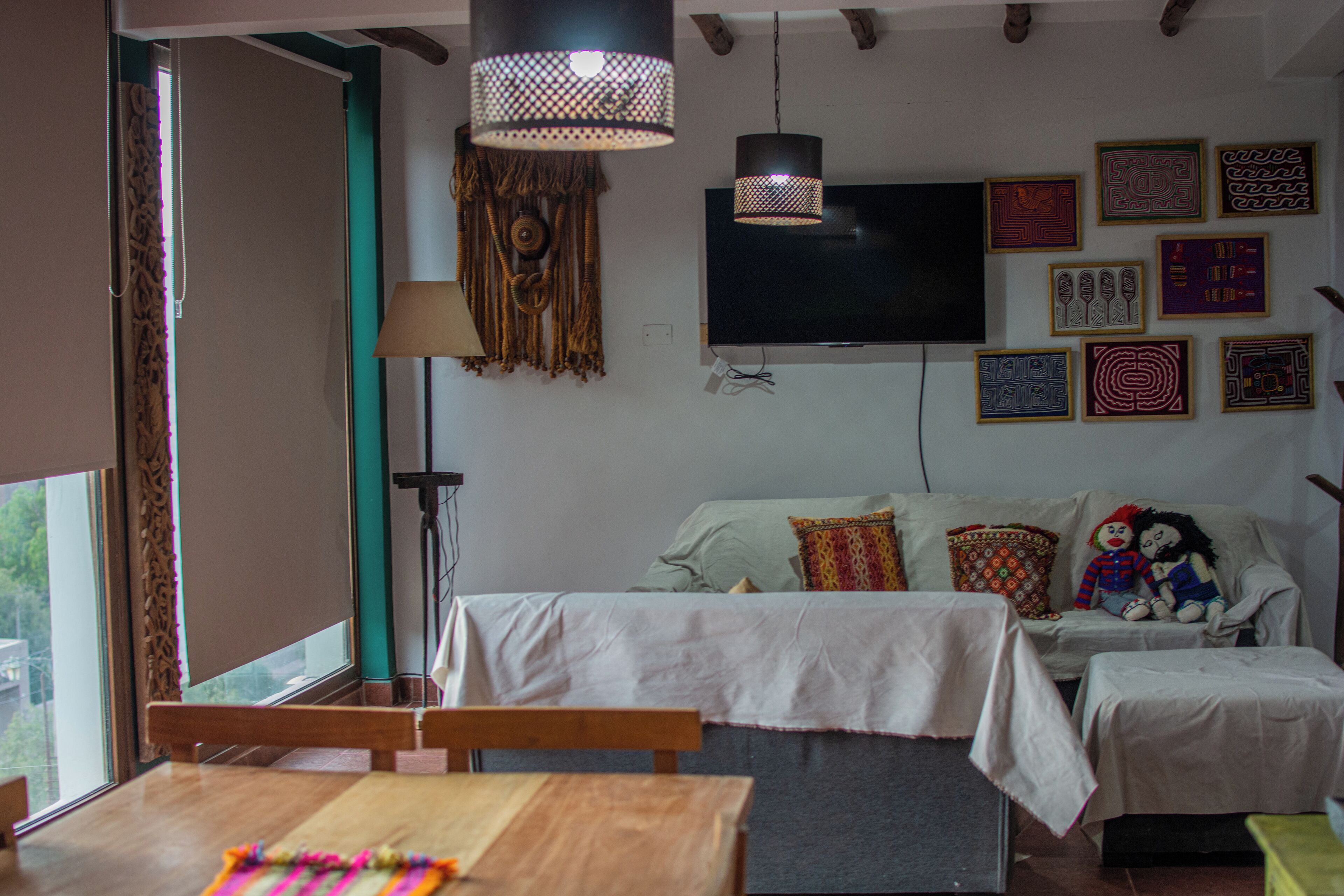 A living room with a TV, patterned wall art, and a dining area with a table and chairs.
