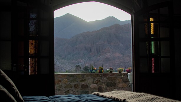 Un dormitorio con vista a las montañas desde un vano abierto.