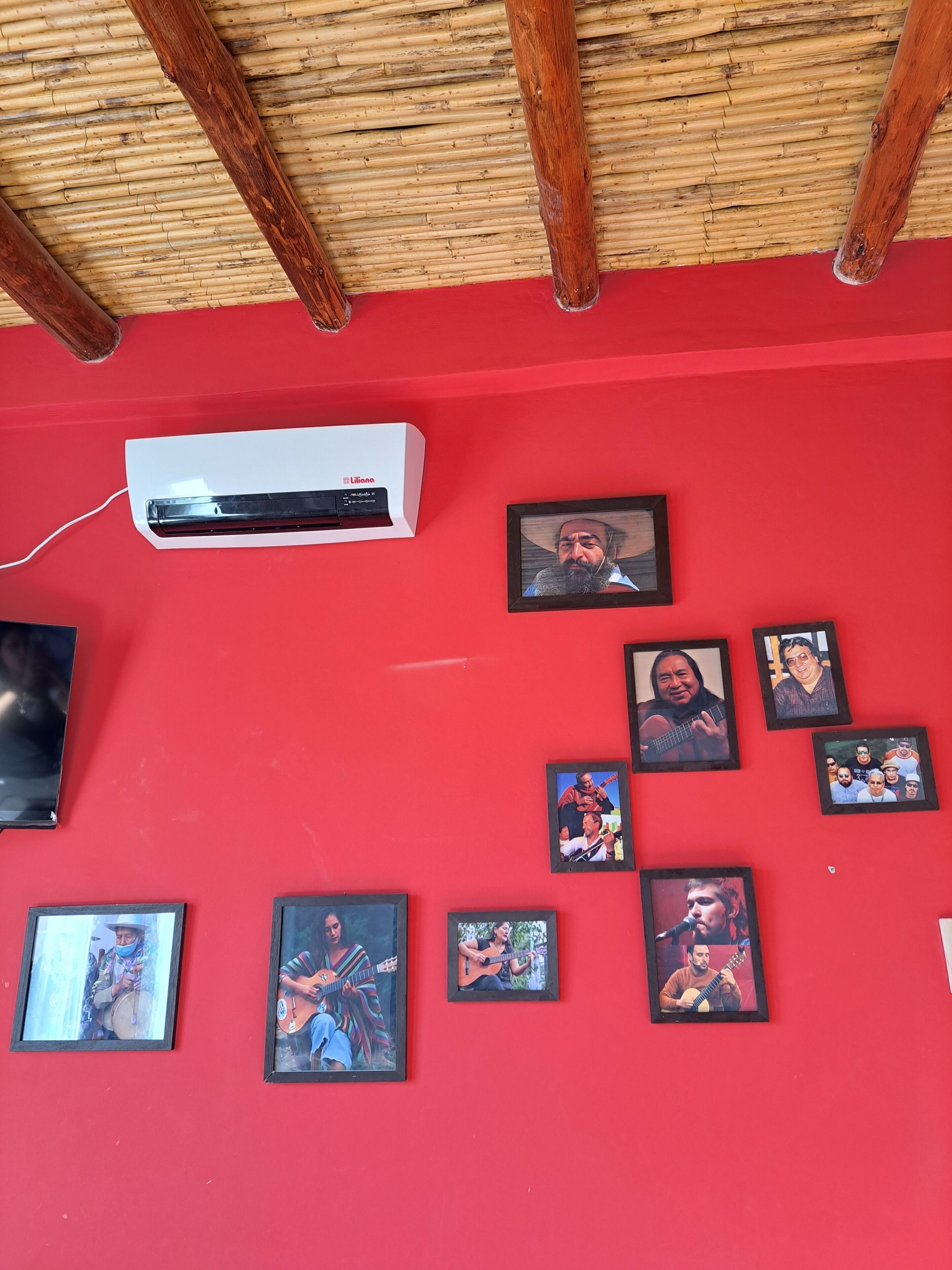 Une pièce avec un mur rouge, des poutres en bois au plafond et un climatiseur fixé au mur.