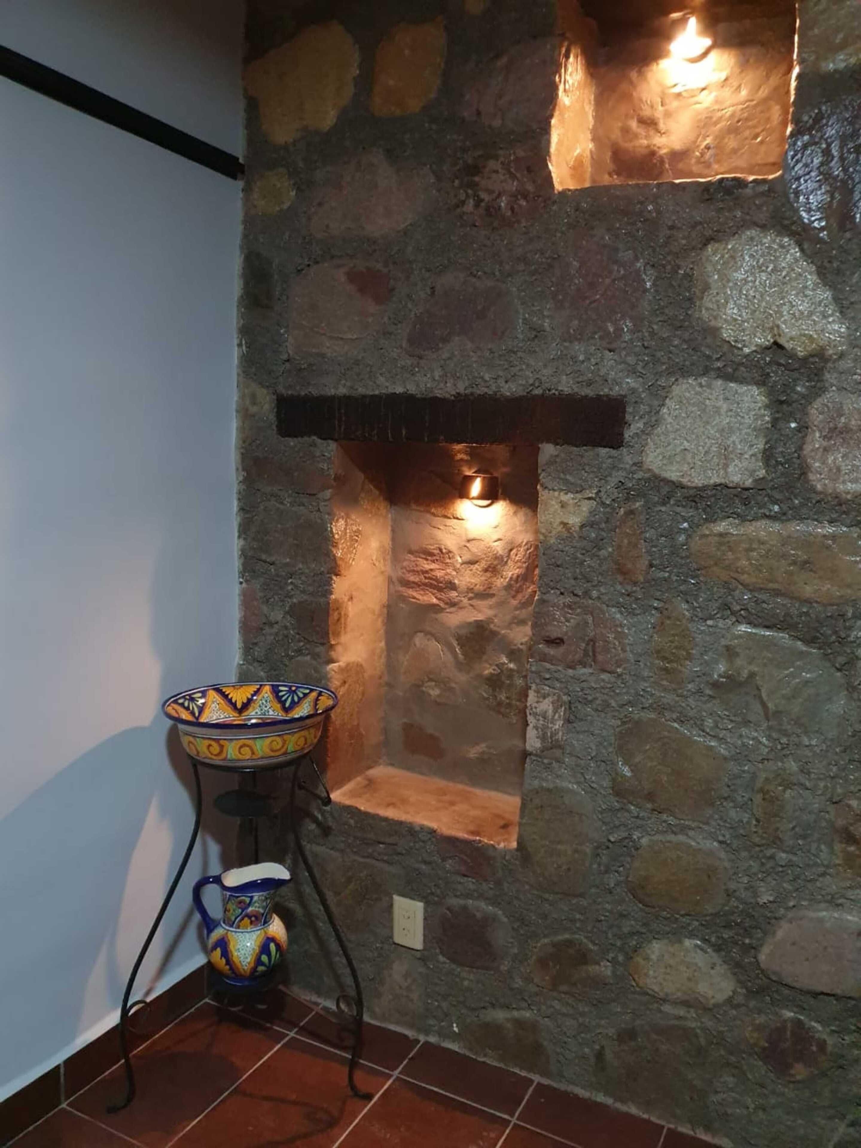 A stone fireplace with a decorative bowl on a stand.