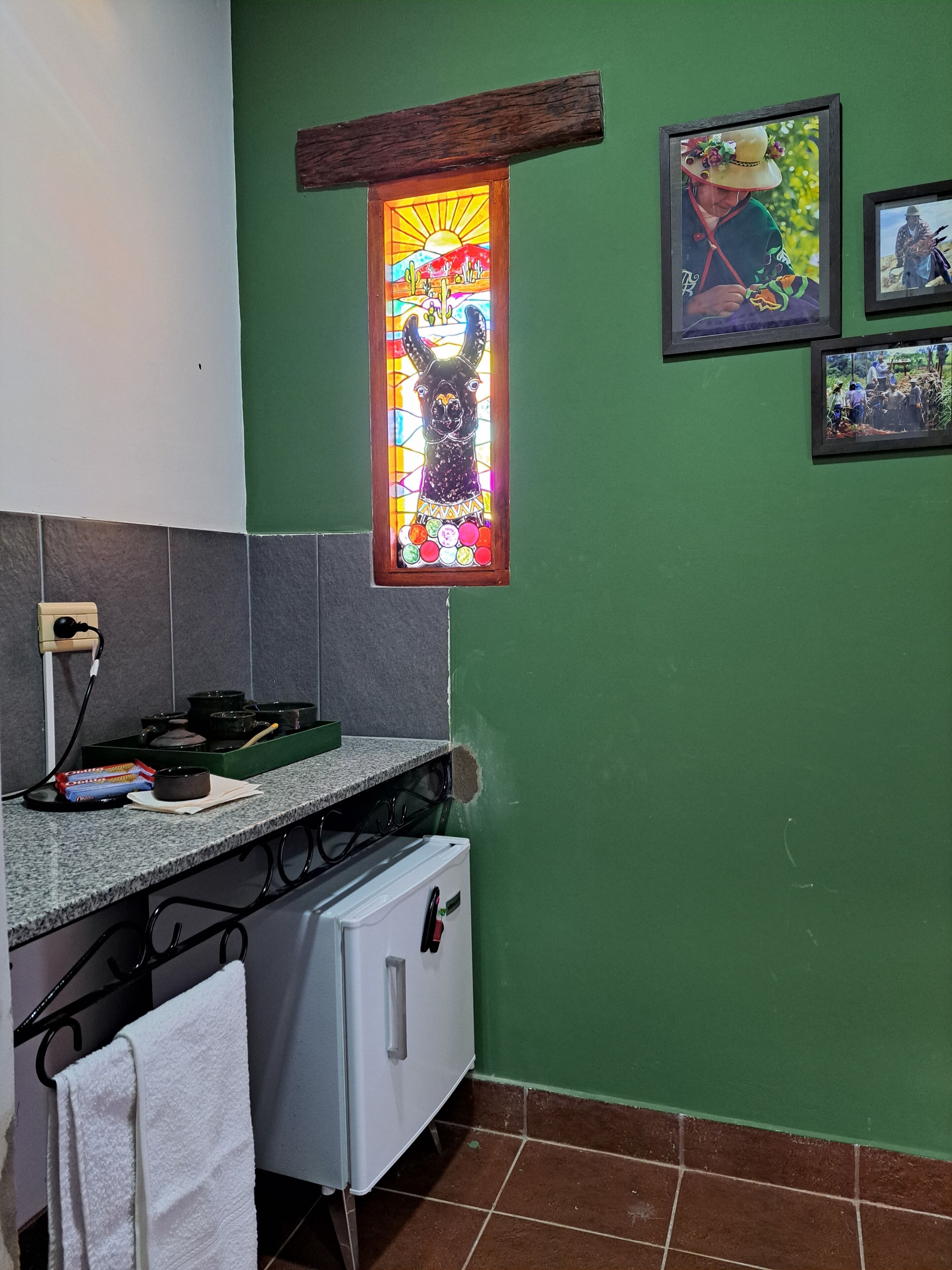 Une cuisine avec un mur vert, un vitrail et un réfrigérateur.