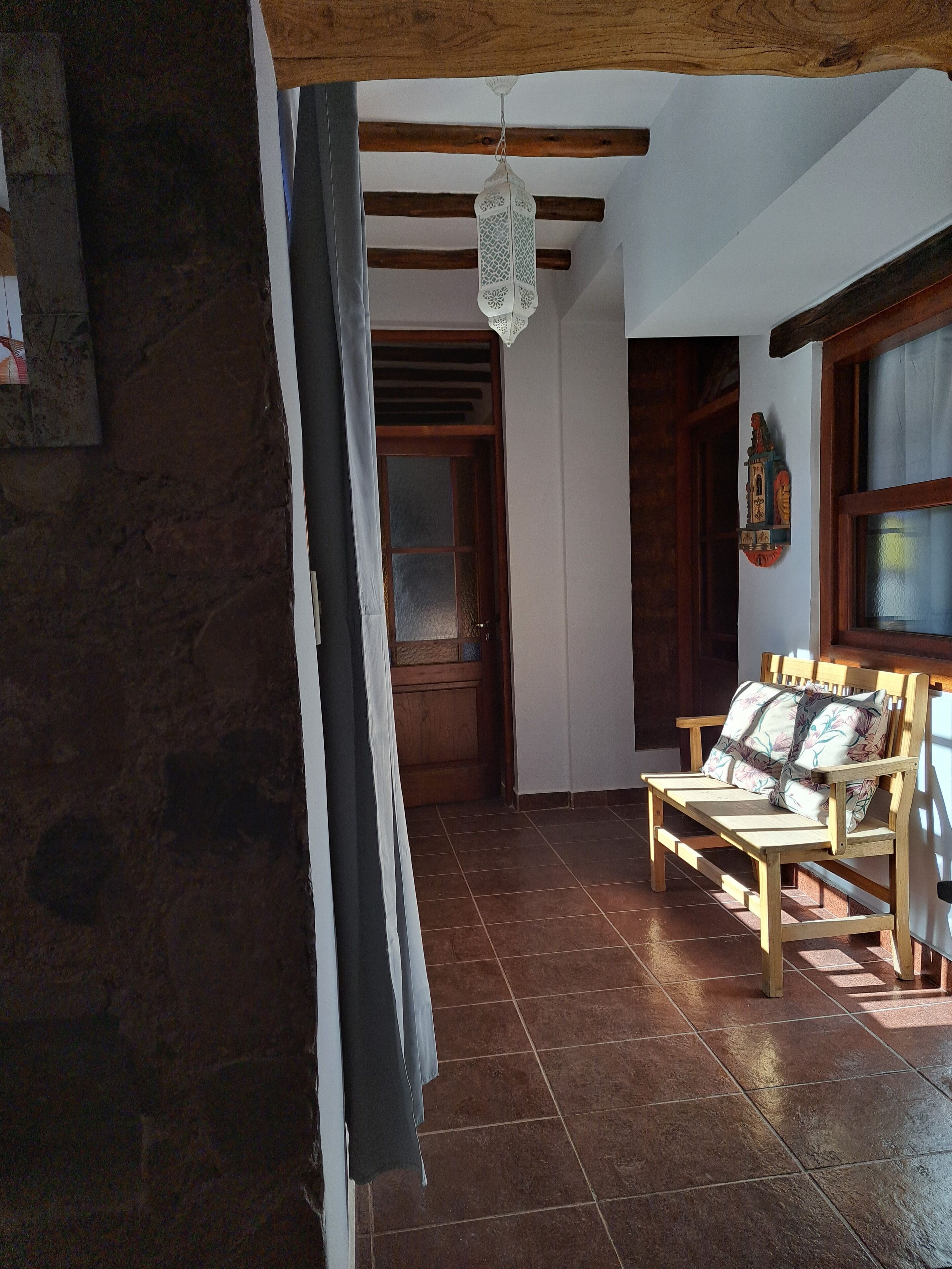 A room with a wooden bench, a hanging lantern, and a door with a frosted glass panel.