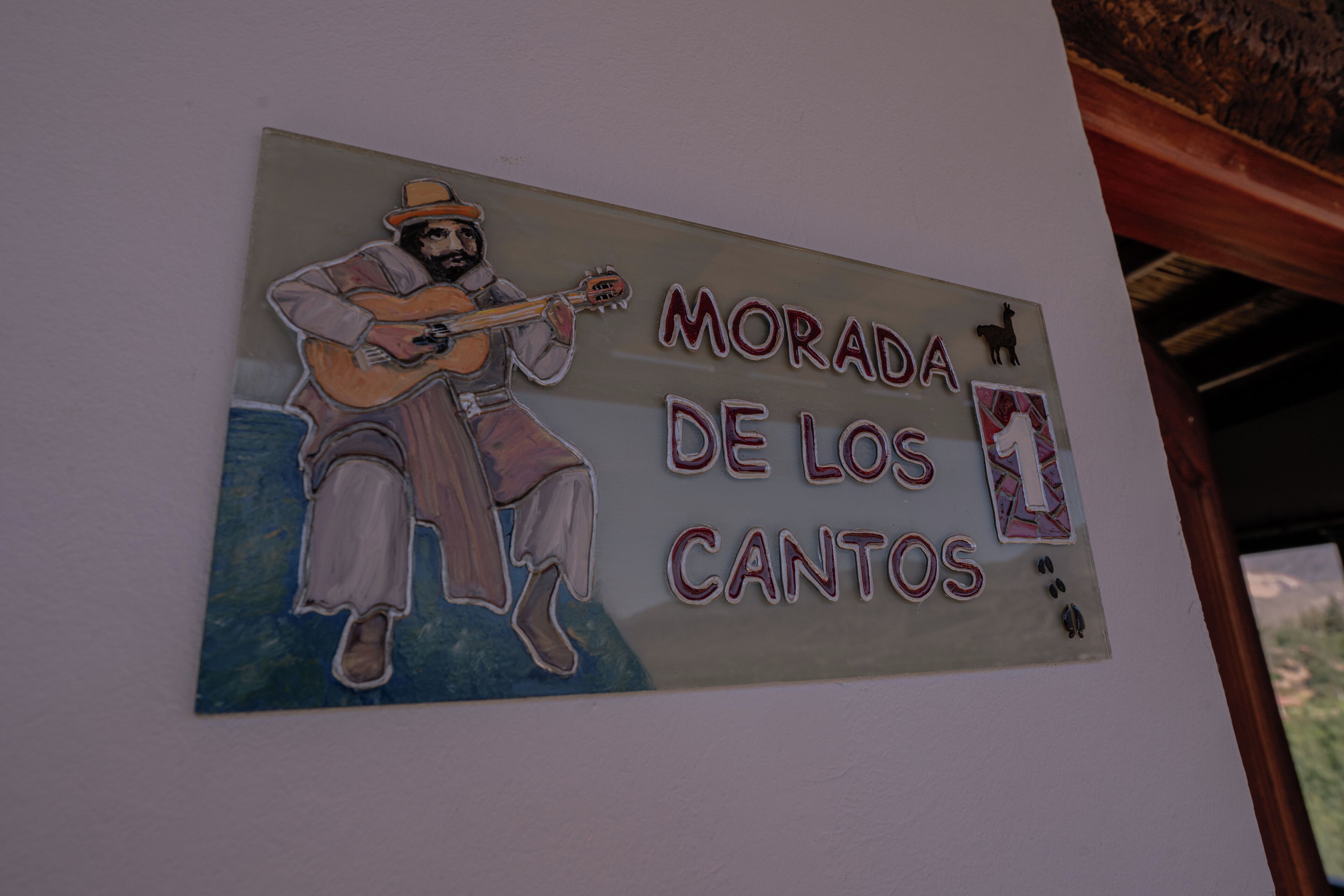 A wall with a mural of a man playing a guitar and the text "MORADA DE LOS CANTOS".