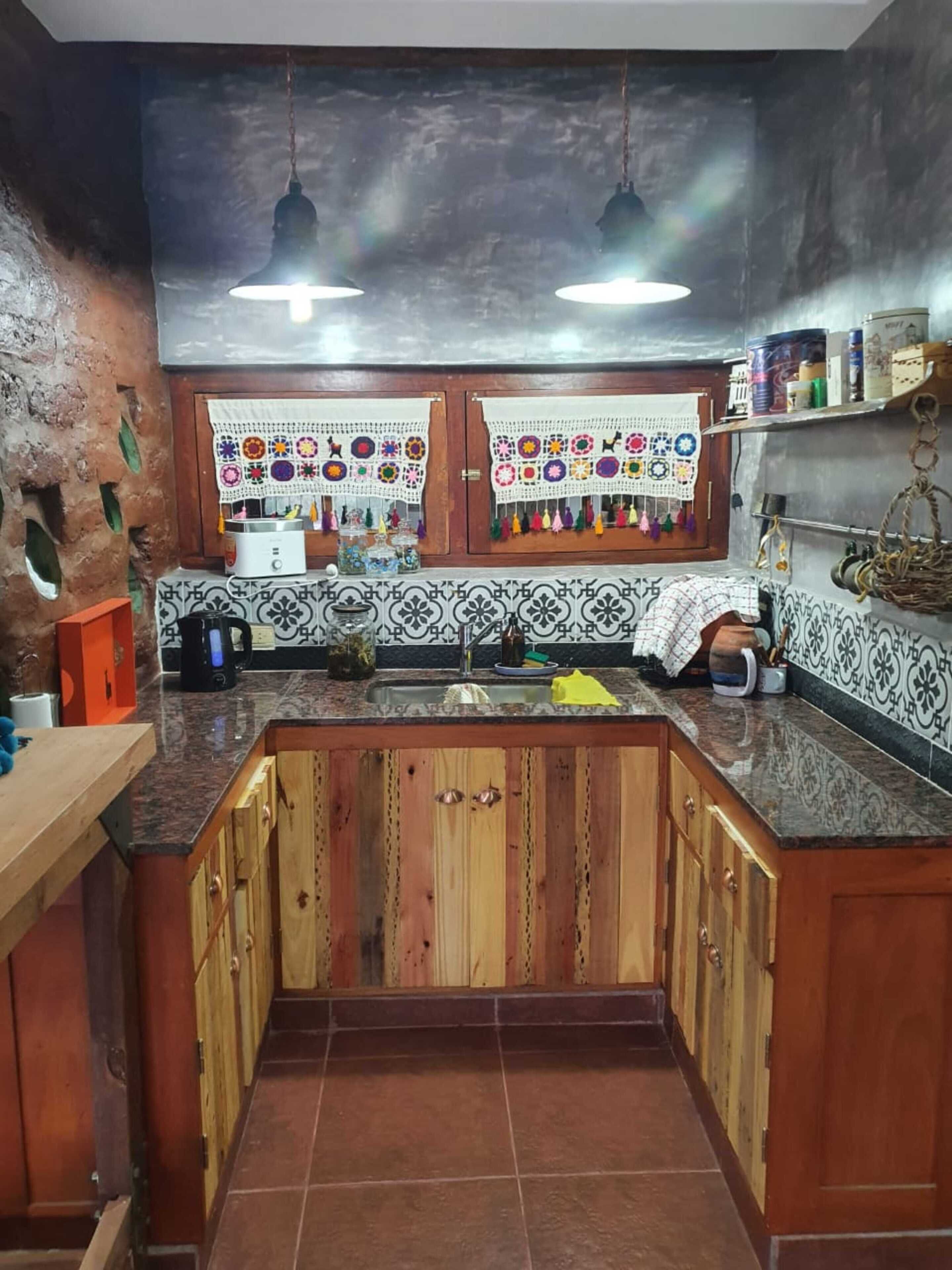 Une cuisine avec des meubles en bois, un dosseret carrelé et des luminaires suspendus.