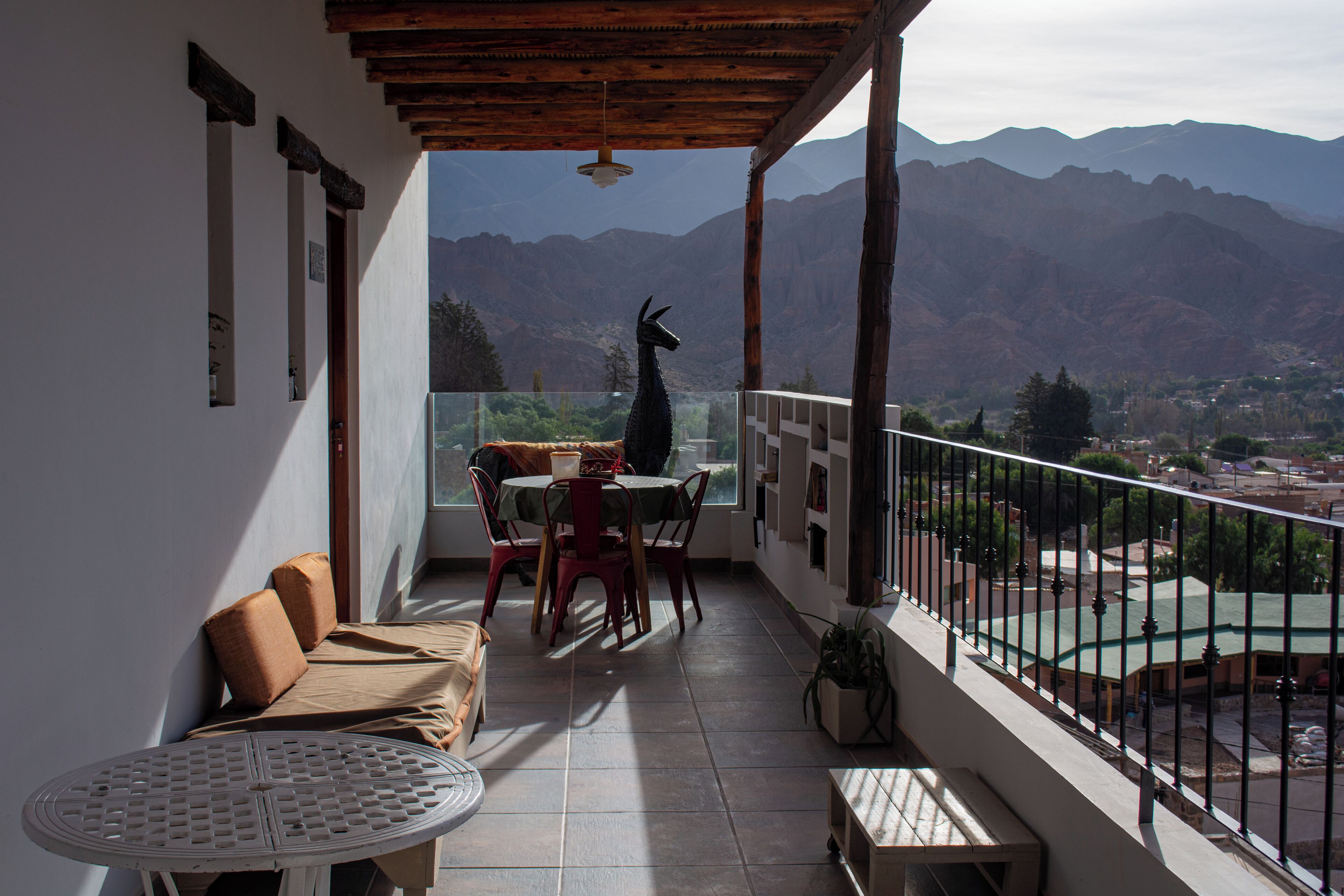 A balcony with a table and chairs, a sofa, and a potted plant.
