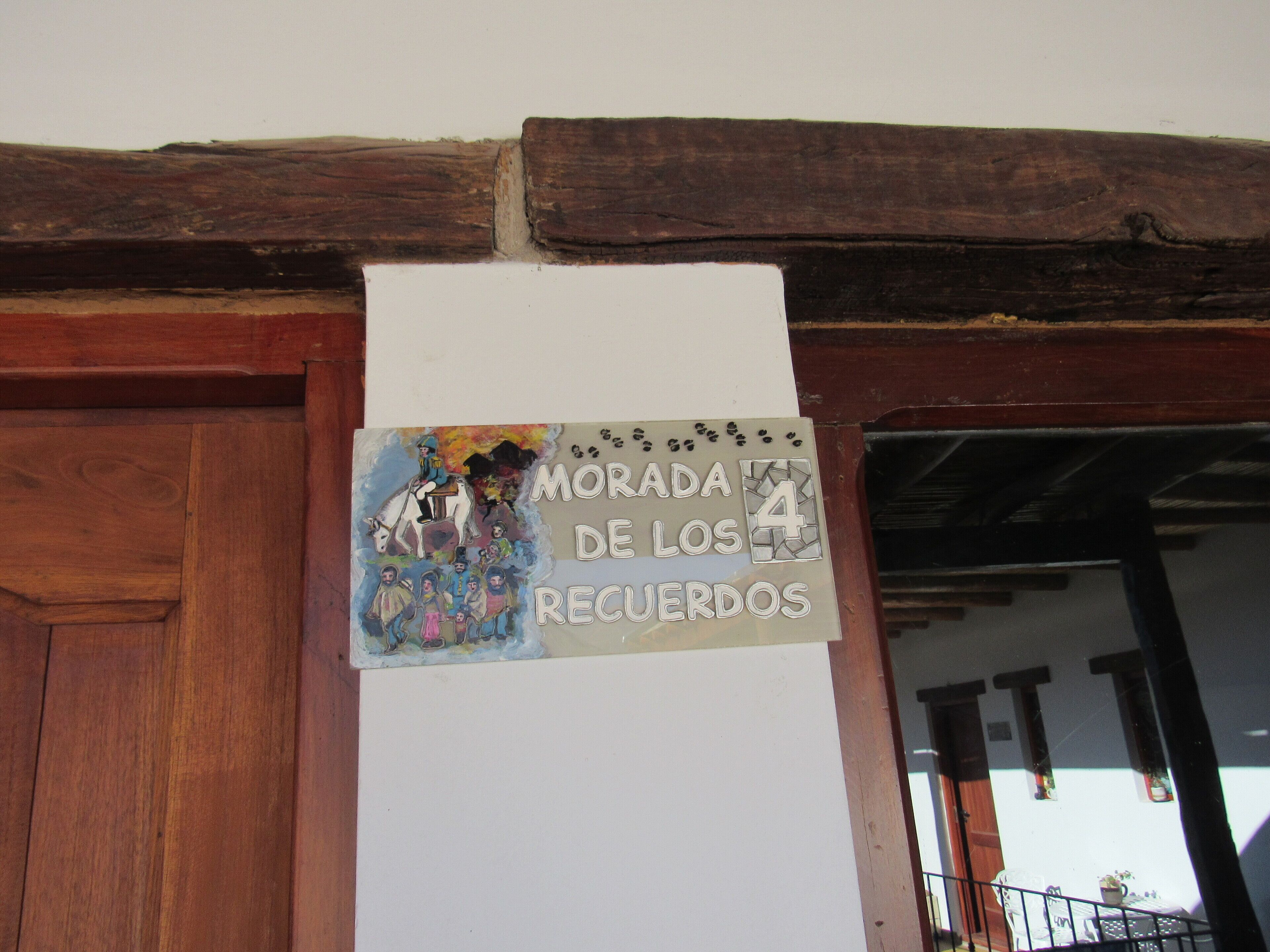A sign with a colorful illustration and text, mounted on a wall above a wooden door.