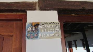 A sign with a colorful illustration and text, mounted on a wall above a wooden door.