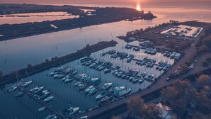 A marina with numerous boats docked, a parking area, and a sunset in the background. - Lodge Tenuta Primero in Grado (Province of Gorizia)
