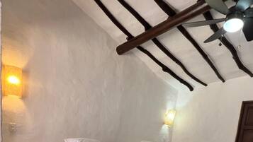A room with two beds, a ceiling fan, and a brick floor.
