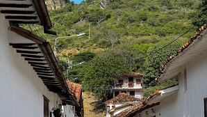 A narrow cobblestone street flanked by white buildings with terracotta roofs, leading up a hillside. - Hotel Don Juan de Dios de Guane (Barichara)