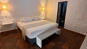 A bedroom with a bed, bedside tables, wall-mounted lights, a ceiling fan, and a wooden beam structure. - Hotel Don Juan de Dios de Guane (Barichara)