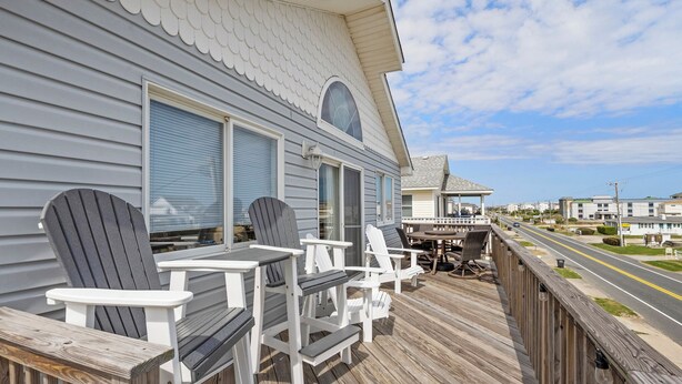 Une terrasse avec des fauteuils Adirondack et une table, donnant sur une rue.