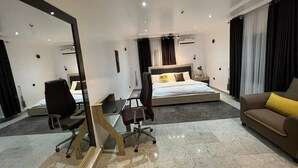 Ein modernes Hotelzimmer mit einem großen Bett, einem Schreibtisch, einem Sessel und einer Couch.
