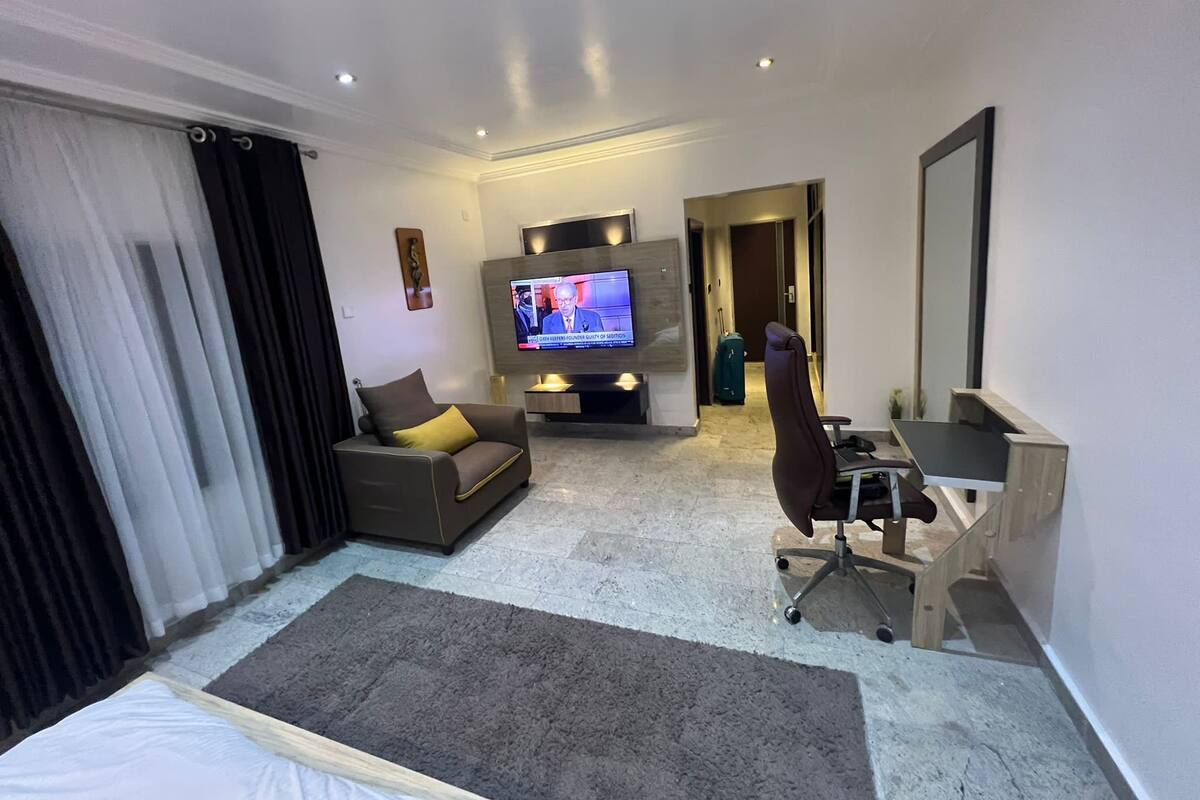 Ein modernes Hotelzimmer mit einer Couch, einem Schreibtisch, einem Fernseher und einem großen Spiegel.