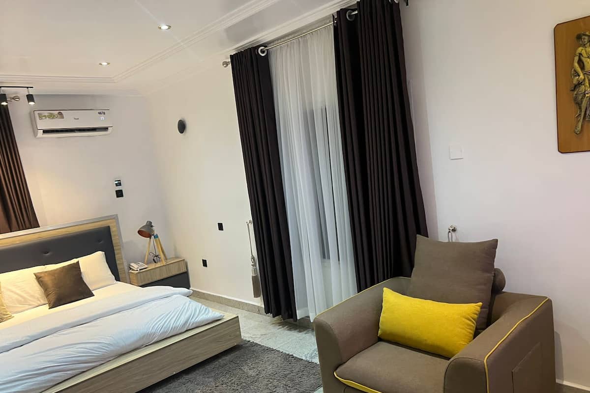 Ein modernes Hotelzimmer mit Bett, einer Couch und einem großen Fenster mit Vorhängen.
