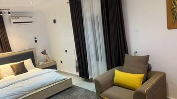 A modern hotel room with a bed, a sofa, and a large window with curtains.