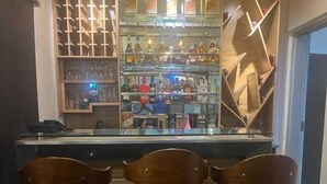 Eine Bar mit drei hölzernen Barhocker und einer Glasvitrine für Spirituosen.