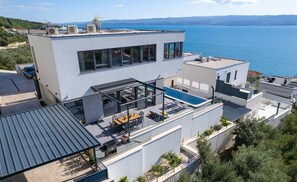Un bâtiment moderne doté d’une piscine sur le toit, de grandes fenêtres et offrant une vue sur la mer.