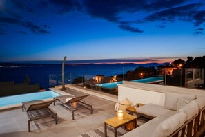 Una terrazza sul tetto con piscina, poltrone relax e divano con vista sul tramonto.