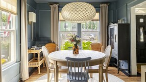 Un coin repas avec une table ronde, des chaises, un luminaire suspendu et une vue sur l’extérieur.