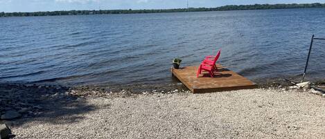 A wooden dock extending into a calm lake with a clear sky.