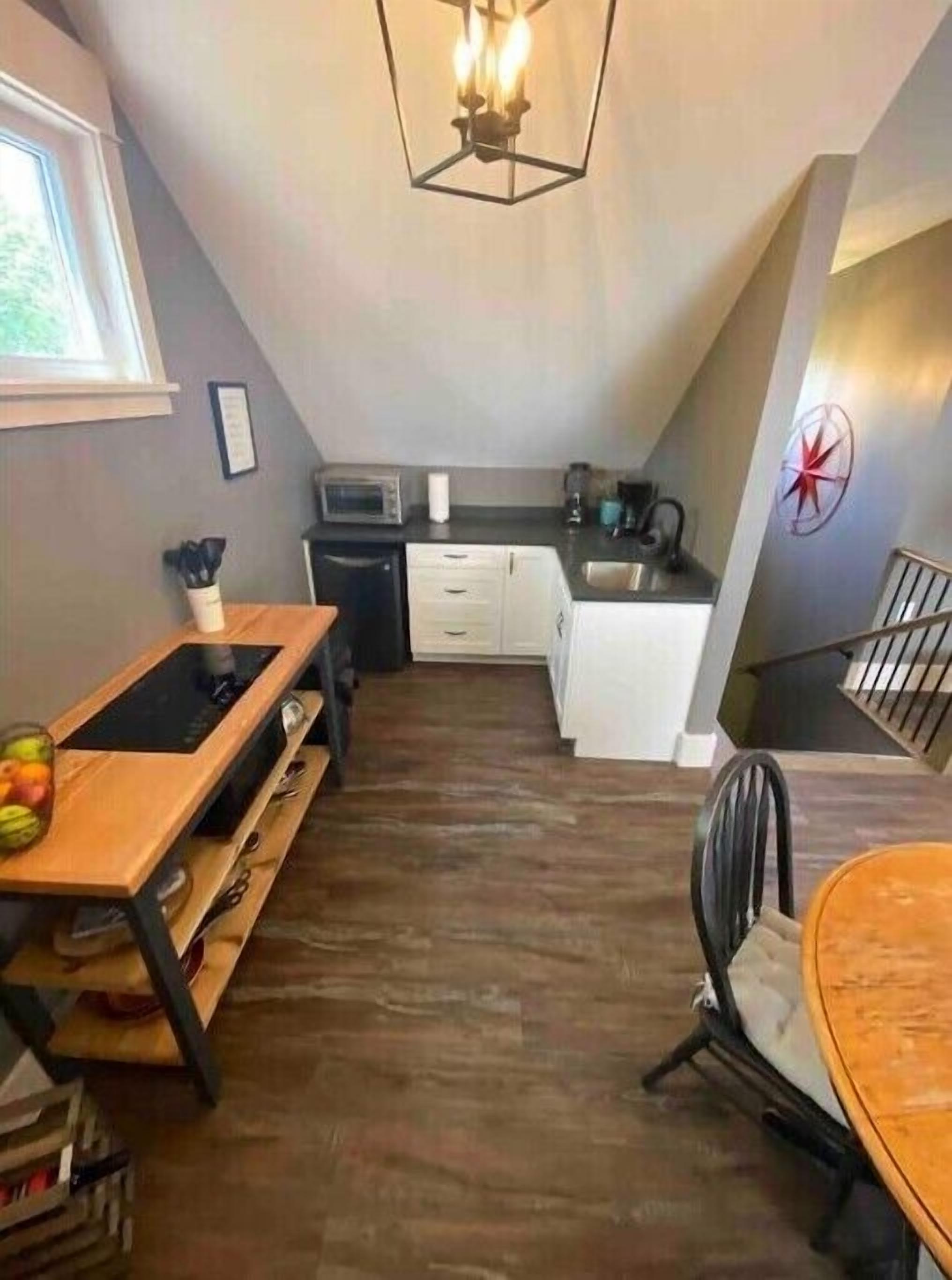 Een kleine keuken met een eethoek, een houten tafel en een moderne kroonluchter.