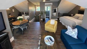 Ein kompakter, moderner Loftraum mit Essbereich, einer Couch, einem Bett und einem Deckenventilator.