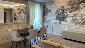 Un espace repas comprenant une table et des chaises, un grand miroir et une fresque murale.