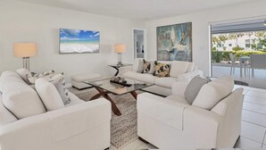 A modern living room with white furniture, a glass coffee table, and artwork on the walls. - RENOVATED 4/3 Canal Front, Pool and Dock (Longboat Key)