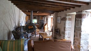 Un intérieur rustique avec des poutres apparentes, des murs en pierre, une cheminée et un coin repas.