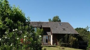 Une maison avec un toit en pente, un porche à l’avant et une pelouse bien entretenue.